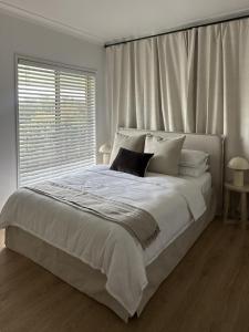 a white bedroom with a large bed with a window at Hillview Studio One in Berry