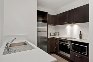 a kitchen with a sink and a stainless steel refrigerator at Quest Dandenong in Dandenong