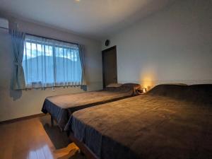 伊东SAKURA Cottage Izukogen的有窗户的房间里有两张床