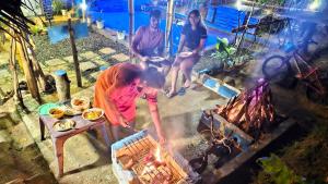 a group of people standing around a grill at Sky Blue Cabin in Kandy