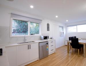 a kitchen with white cabinets and a sink and a table at Pool, Games & fun - Family Retreat! in Boronia