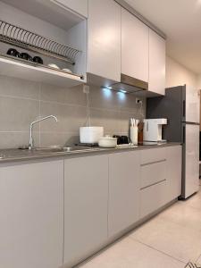 a white kitchen with a sink and a refrigerator at StayCO - D'Millenia Residences - Studio Unit in Kuching