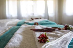 a bed with white towels and red flowers on it at Gondwana Hakusembe River Lodge in Rundu