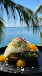 a sandwich with vegetables on a black plate with lemons at Casa China Guesthouse & Hostal in Bacalar