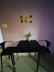 Una mesa negra con dos sillas y una planta. en Niroda Guest House, Jorhat, en Jorhat