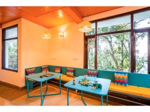 a dining room with two tables and windows at goSTOPS Mukteshwar in Mukteswar
