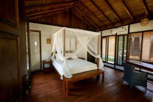 a bedroom with a bed with a mosquito net at Bobocha Tangkoko Nature Resort in Bitung