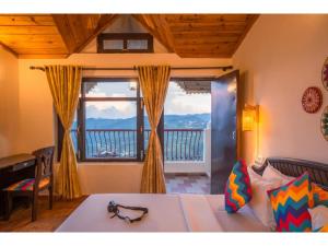 a bedroom with a bed and a large window at goSTOPS Mukteshwar in Mukteswar