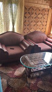 ein Wohnzimmer mit 2 Sofas und einem Glastisch in der Unterkunft Mir heritage in Srinagar + 1 Foto