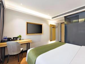 大同市にあるGreenTree Inn Express Datong High-Speed Railway Station Old City Wallのベッド、机、テレビのある寝室
