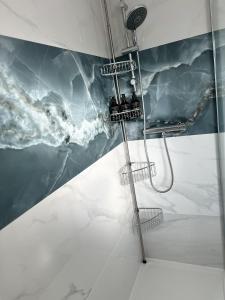 une douche dans une salle de bain avec une fresque murale représentant des vagues dans l'établissement Ama comfort Stay, à Hythe