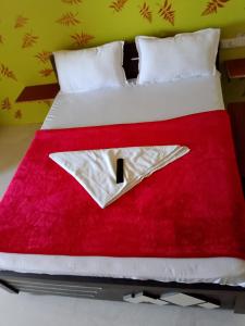 a bed with a red and white blanket on it at hotel shreejee in Himatnagar