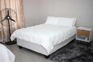 a bedroom with a white bed and a fan at LESEGO LA RONA Villa in Manamakgoteng