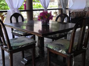 een houten tafel met stoelen en een vaas met bloemen erop bij Karibuni, Villa 107, Beachfront Stay with Restaurant, Pool & Bar in Malindi