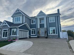 una casa azul con una entrada delante de ella en Walkout basement suite with canal view near airport, en Airdrie