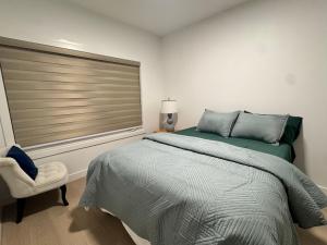 Un dormitorio con una cama y una ventana y una silla. en Walkout basement suite with canal view near airport, en Airdrie