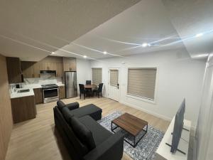 Una sala de estar con un sofá y una mesa y una cocina. en Walkout basement suite with canal view near airport, en Airdrie