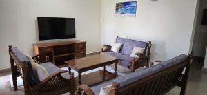 a living room with a couch and a table and a tv at Diani Airport View Apartments in Diani Beach