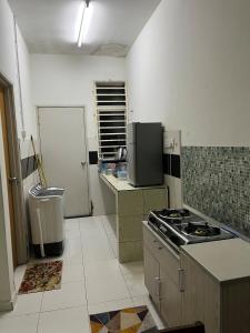 a small kitchen with a stove and a refrigerator at Dua Puteri Homestay 