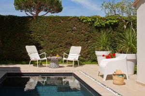 un patio con 2 sillas y una piscina en Oustau Camarguen Hôtel & Spa en Le Grau-du-Roi