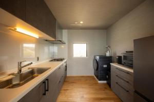 een kleine keuken met een spoelbak en een magnetron bij Yunagi 夕凪  +71 foto's