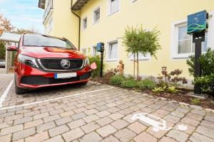 een rode auto geparkeerd voor een huis bij Mikro Apartments Erding in Erding