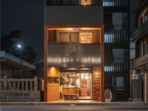 a modern house with a glass facade at night at LiVEMAX Hostels Kyoto Ekimae in Kyoto