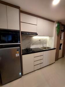 eine Küche mit weißen Schränken und einem Edelstahlkühlschrank in der Unterkunft Apartemen Meikarta by WhiteBox in Tegaldanas