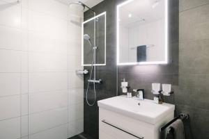 ein Badezimmer mit einem weißen Waschbecken und einer Dusche in der Unterkunft Apartment Stockhorn in See- und Bergnähe, modern, mit Balkon, 4 Gäste in Einigen + 64 Fotos