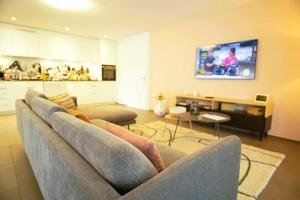 un soggiorno con un divano e una TV a parete di Apartment Niesen Lake Stay a Einigen
