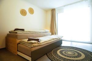 2 letti in una camera con finestra e tappeto di Apartment Niesen Lake Stay a Einigen