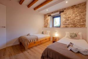 two beds in a room with a stone wall at The Stone House naturaleza y confort in Santibáñez de Villacarriedo