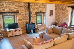 a living room with a couch and a tv at The Stone House naturaleza y confort in Santibáñez de Villacarriedo