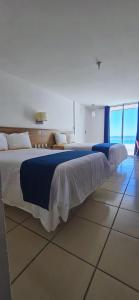 a bedroom with a large bed with blue and white sheets at Hotel Playamar in Mazatlán