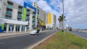 a white car driving down a city street with buildings at Hotel Playamar in Mazatlán