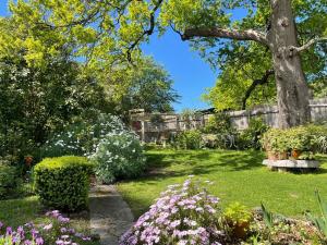 un jardin avec un arbre, des fleurs et une clôture dans l'établissement PET Friendly Miners Cottage 'Baraka BnB', à Kalorama