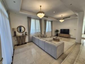 a living room with a couch and a television at Élégante Villa de Luxe 5 Chambres avec Piscine Privée in Dubai