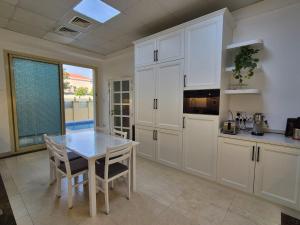 a kitchen with white cabinets and a table at Élégante Villa de Luxe 5 Chambres avec Piscine Privée in Dubai