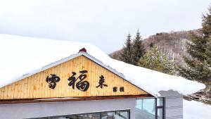 a sign on a building with snow on it at Xuegu Xuefu Lai Inn in Wuchang