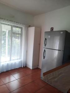 a kitchen with a stainless steel refrigerator and a window at Sea shells self catering in Hibberdene