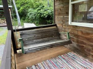 eine Holzbank auf einer Veranda mit einem Fenster in der Unterkunft Bitter Goose Cabin in Barnettstown + 1 Foto