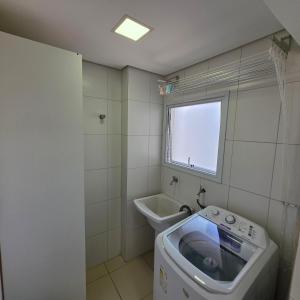 a washing machine in a bathroom with a window at Encontro marcado in Praia Grande