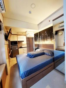 ein Schlafzimmer mit einem großen Bett mit blauer Bettwäsche in der Unterkunft Apartemen Meikarta by WhiteBox in Tegaldanas