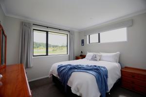 een slaapkamer met een groot bed en twee ramen bij Forest Charm by the Beach in Waitarere