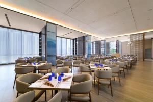 a restaurant with tables and chairs and windows at HARRIS Hotel & Suites Nagoya Batam in Nagoya