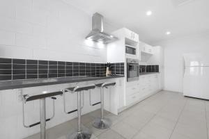 a white kitchen with a counter and a refrigerator at The Coastal Escape - Games & Vibes in Gold Coast