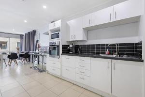 a kitchen with white cabinets and a table in it at The Coastal Escape - Games & Vibes in Gold Coast +12 photos