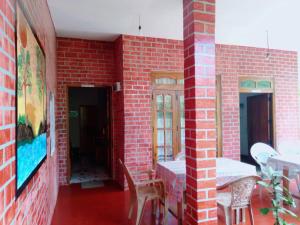 a room with a red brick wall with a table and chairs at Ella Tea Land View in Ella