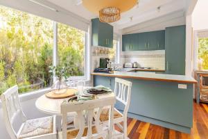 eine Küche mit grünen Schränken sowie einem Tisch und Stühlen in der Unterkunft Cosy 2 Bedroom Cottage with spabath and fireplace in Mount Dandenong