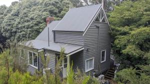 ein Haus an der Seite eines Hügels mit Bäumen in der Unterkunft Cosy 2 Bedroom Cottage with spabath and fireplace in Mount Dandenong + 23 Fotos